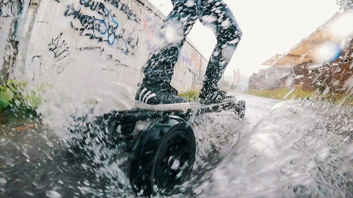 Rider splashing through water on an ONSRA electric skateboard in the rain