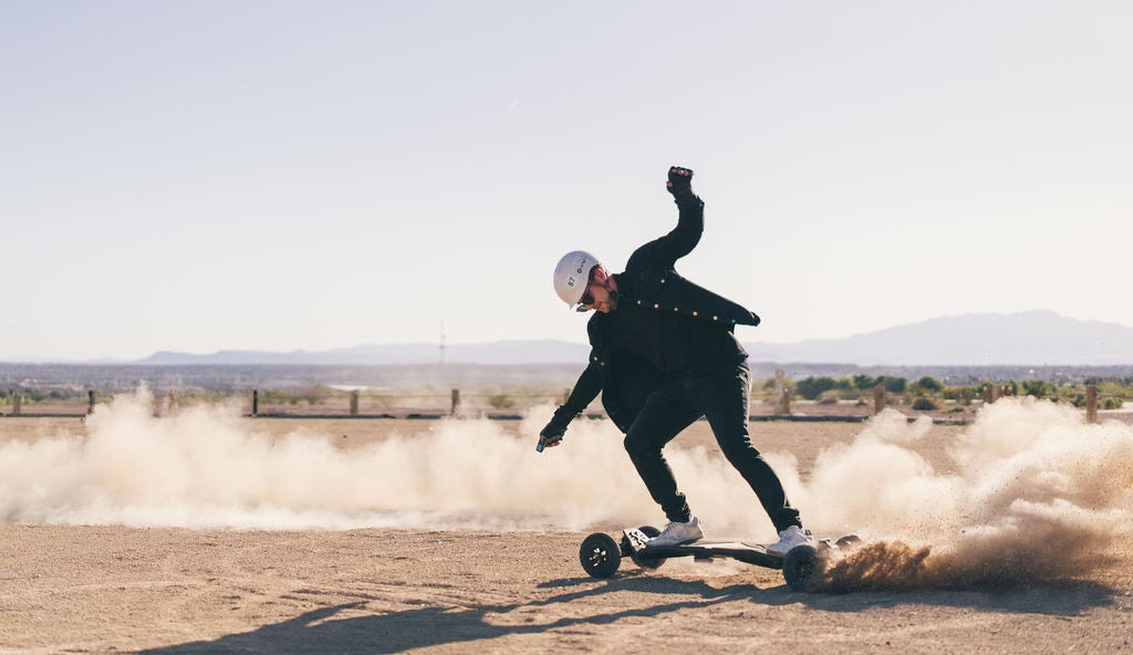 Rider carving an ONSRA electric skateboard through desert dust