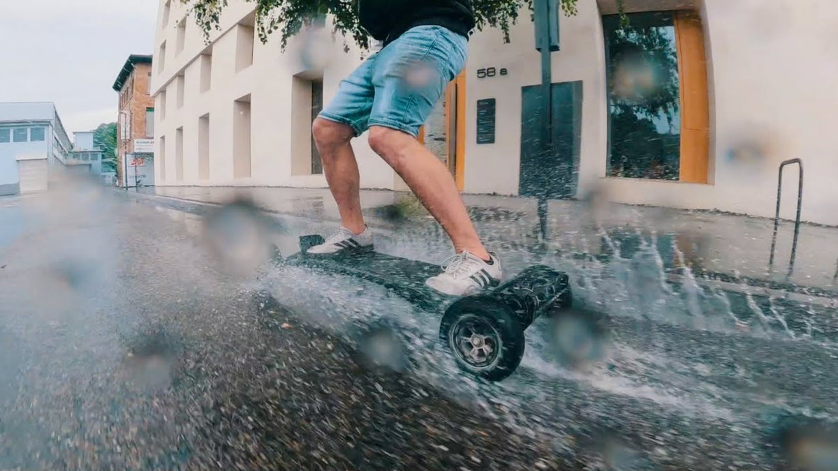 Rider splashing through a wet street on an ONSRA electric skateboard in a rain test